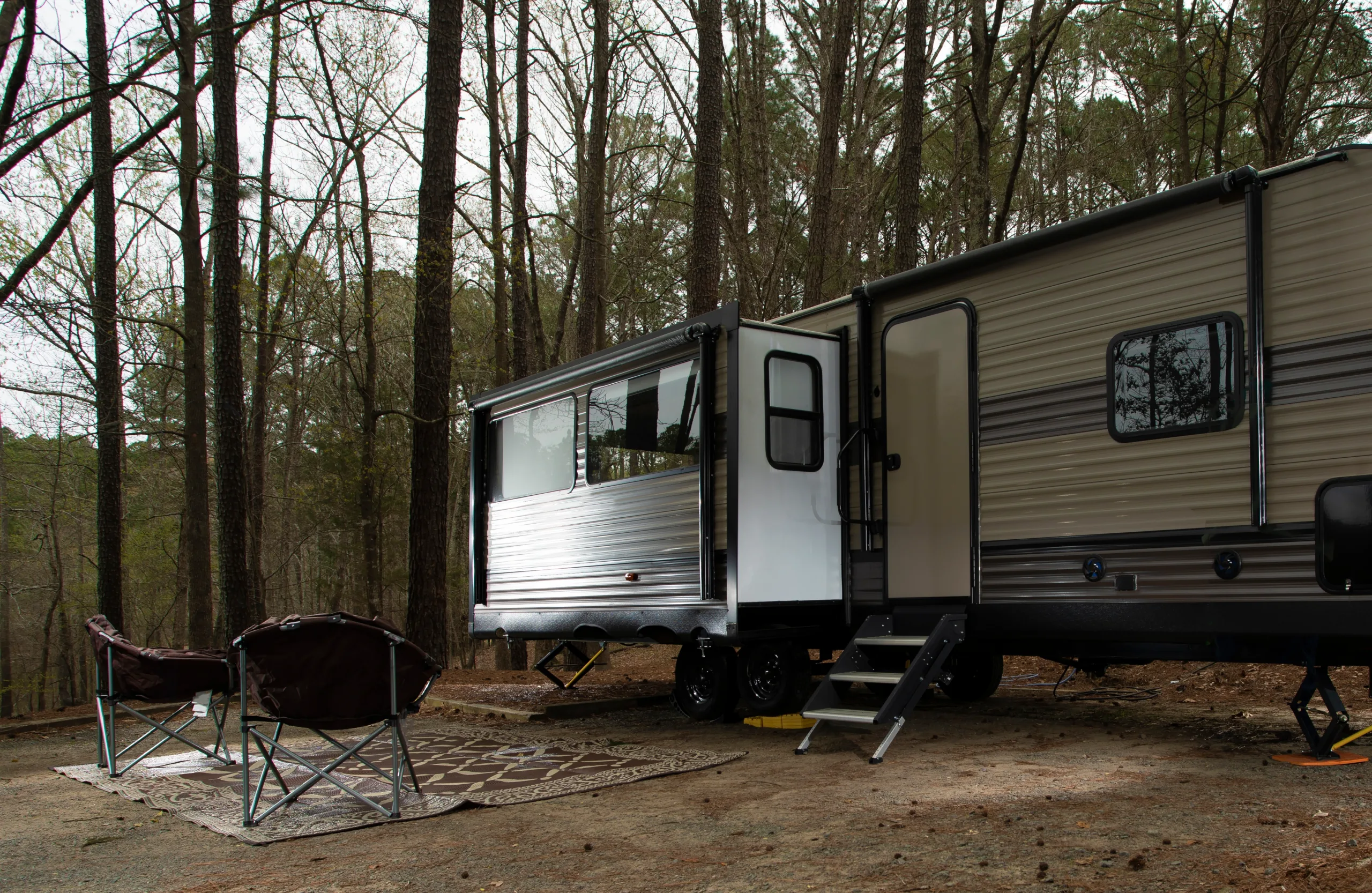 slide out camper trailer parked in woods
