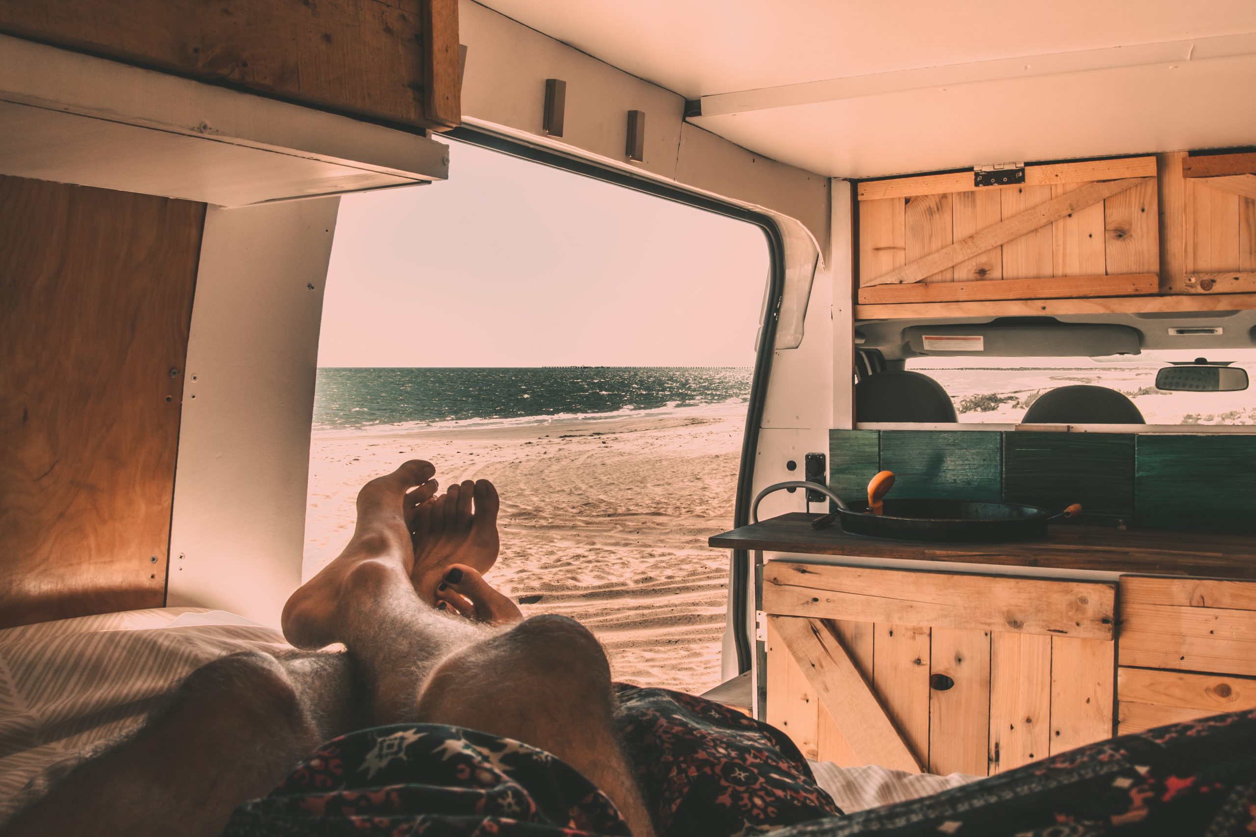 View of a beach from the bed of a camper van - DIY camper van