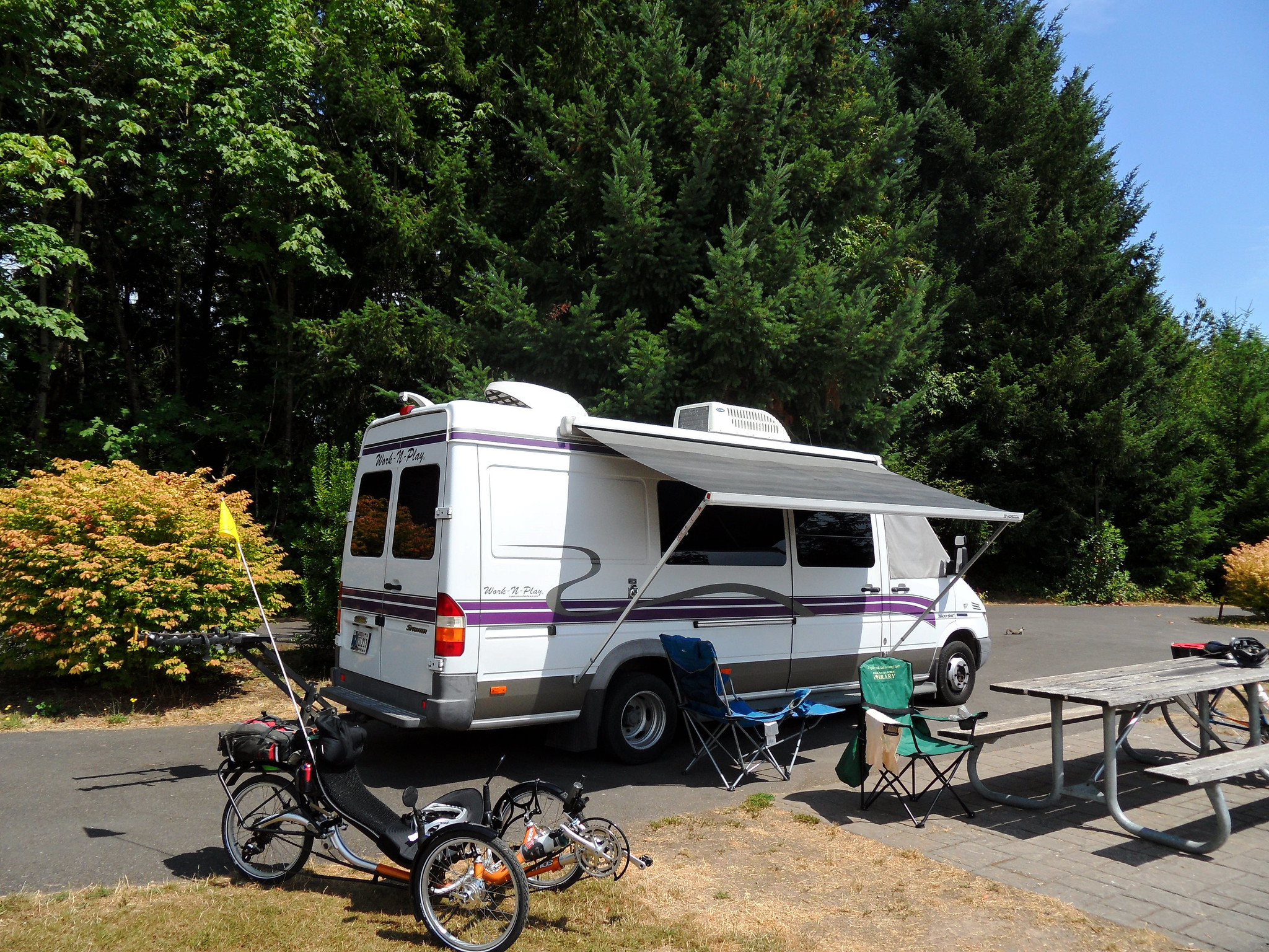 White and marron Sprinter van conversion parked in a campsite at Champoeg State Park in Oregon on a clear and sunny day
