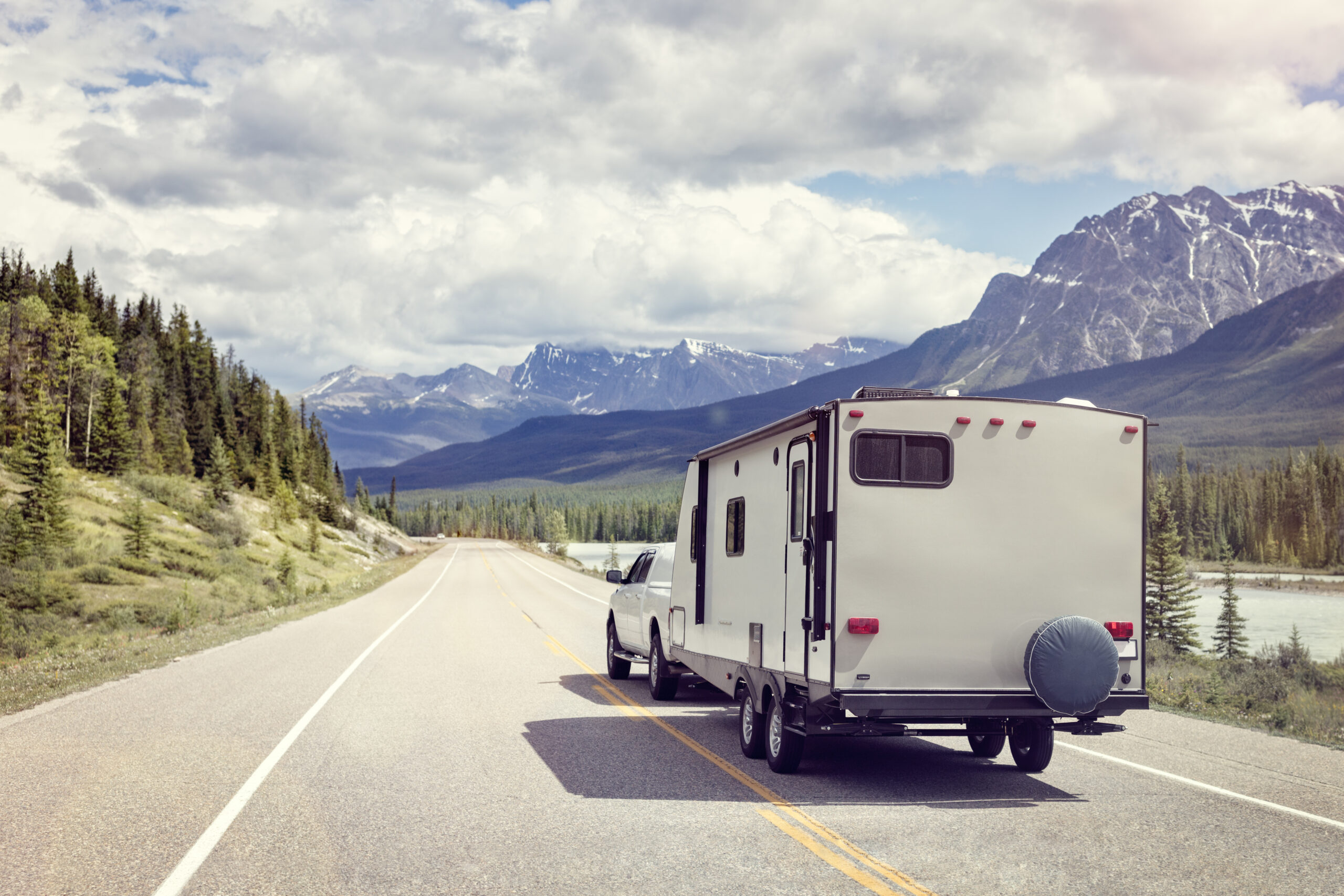 A pickup truck towing an RV through scenic landscape.