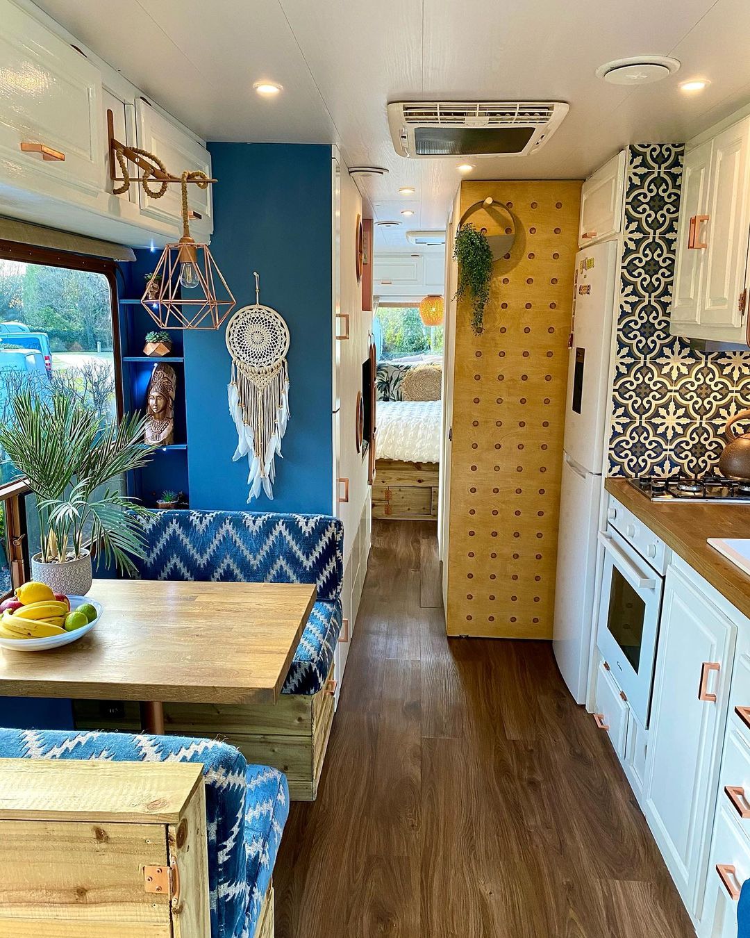 RV interior painted with bright blue walls, chevron patterned cushions, and boho accents