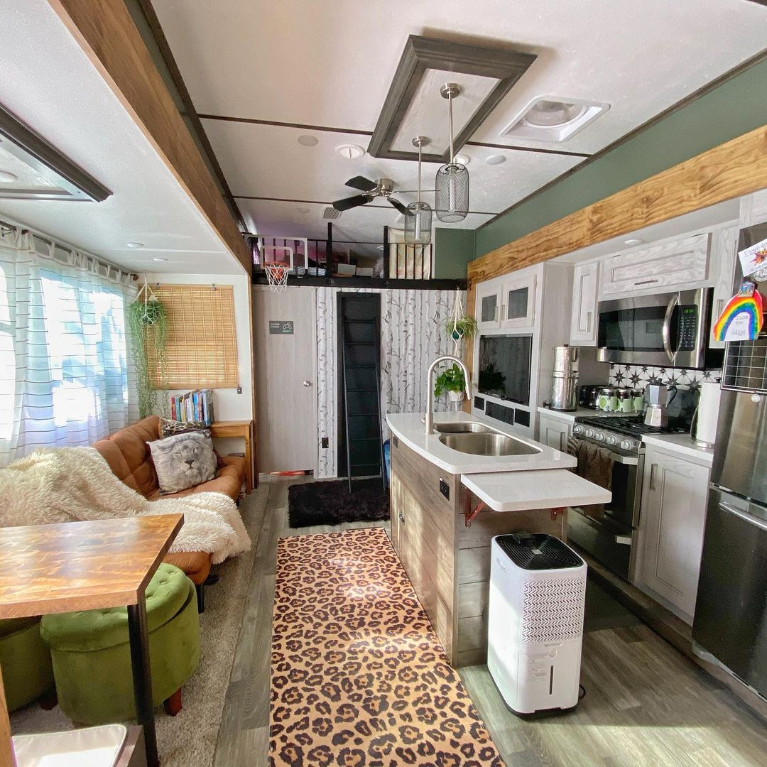 RV interior shot with a spotted rug, sage green walls, and starburst backsplash.