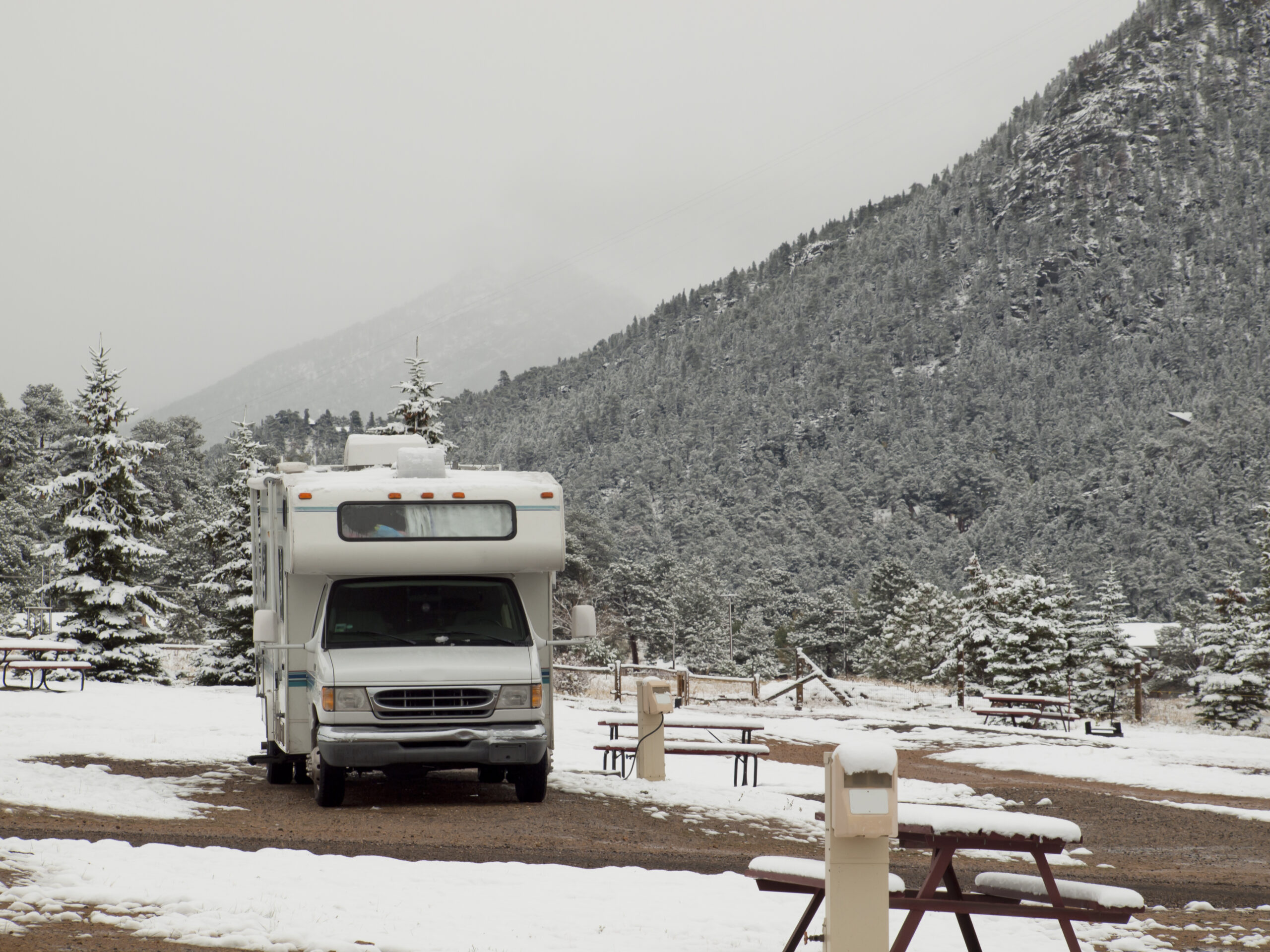 Single RV sits in show covered campsite in mountains - RV warranty