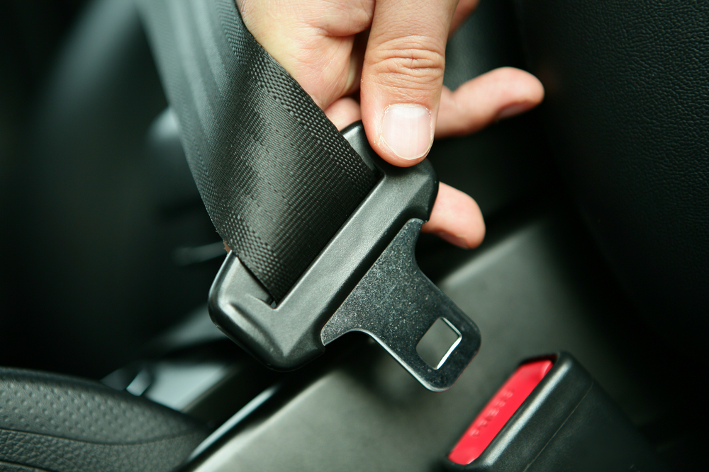 Hand inserting seat belt into latch.