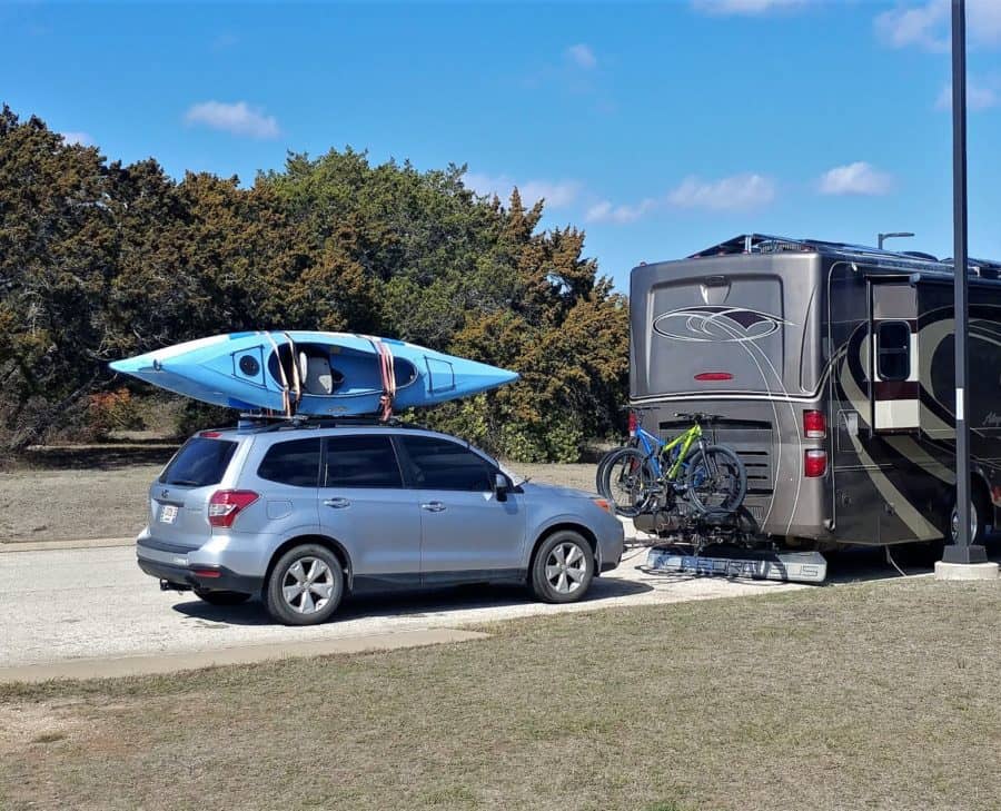 Motorhome with bikes towing a car with kayaks.