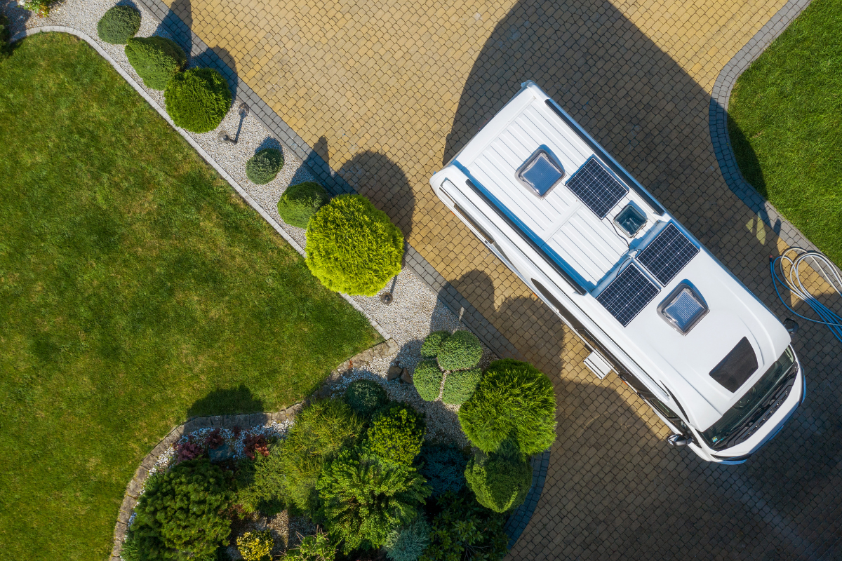 Overhead view of RV with solar panels parked on stone driveway in well landscaped yard - how many solar panels do I need for my RV?