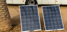 Two solar panels set up on the ground beside a motorhome - how many solar panels do I need for my RV?