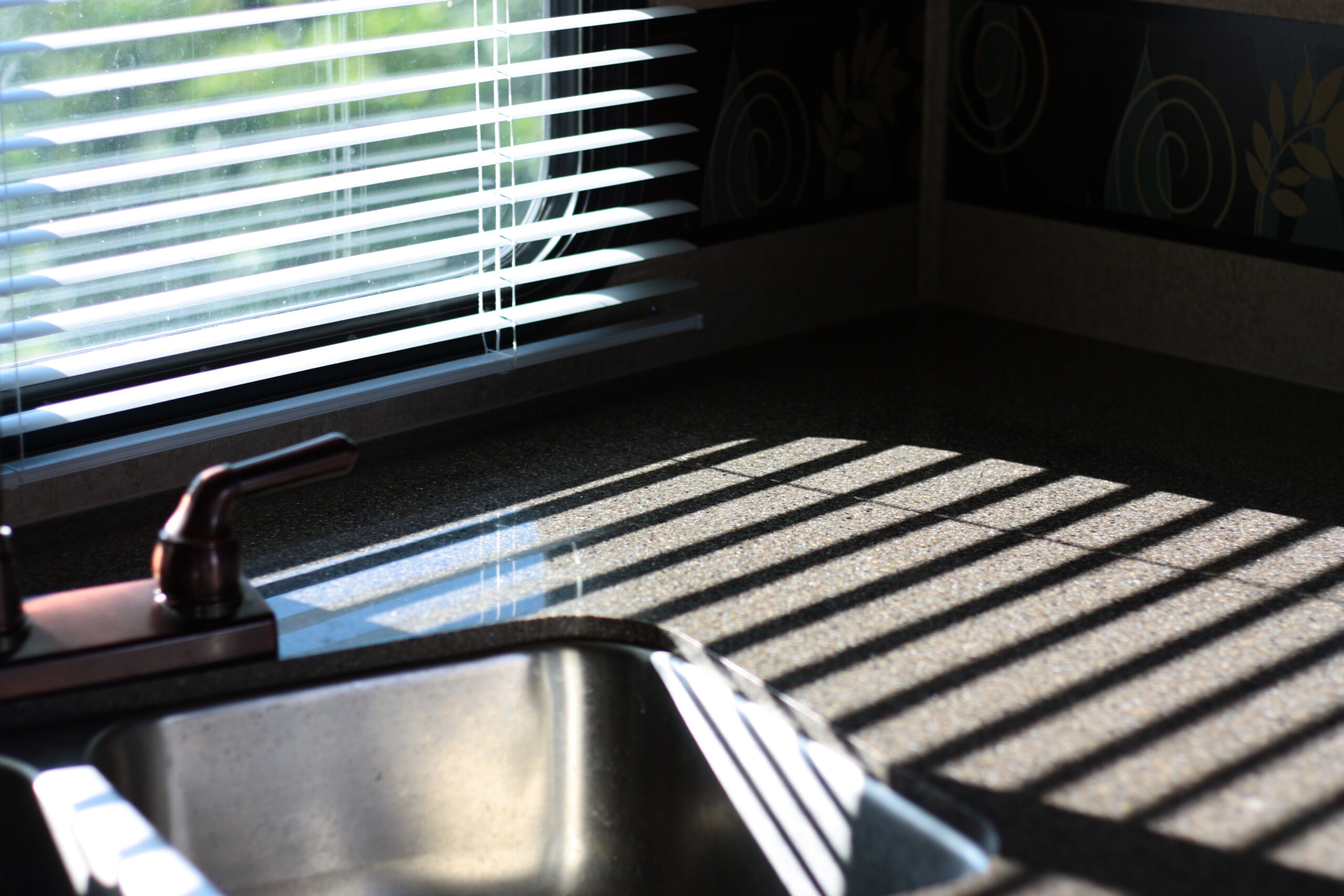 sunlight through blinds on kitchen counter - feature image for How To Fix RV Blinds