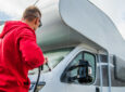 man washing an RV with a pressure washer - feature image for How To Dewinterize An RV