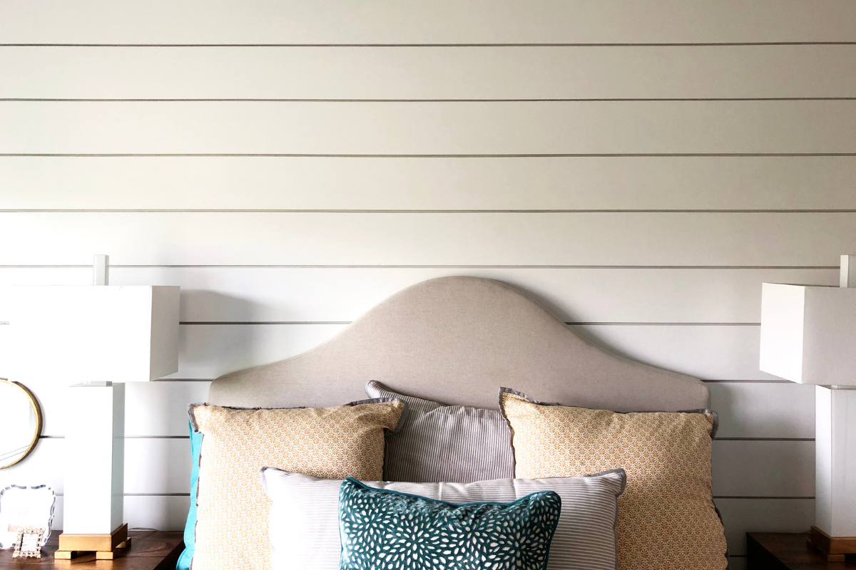 Grey, arched, headboard with colorful pillows against a white shiplap wall - replacing RV wall paneling. 