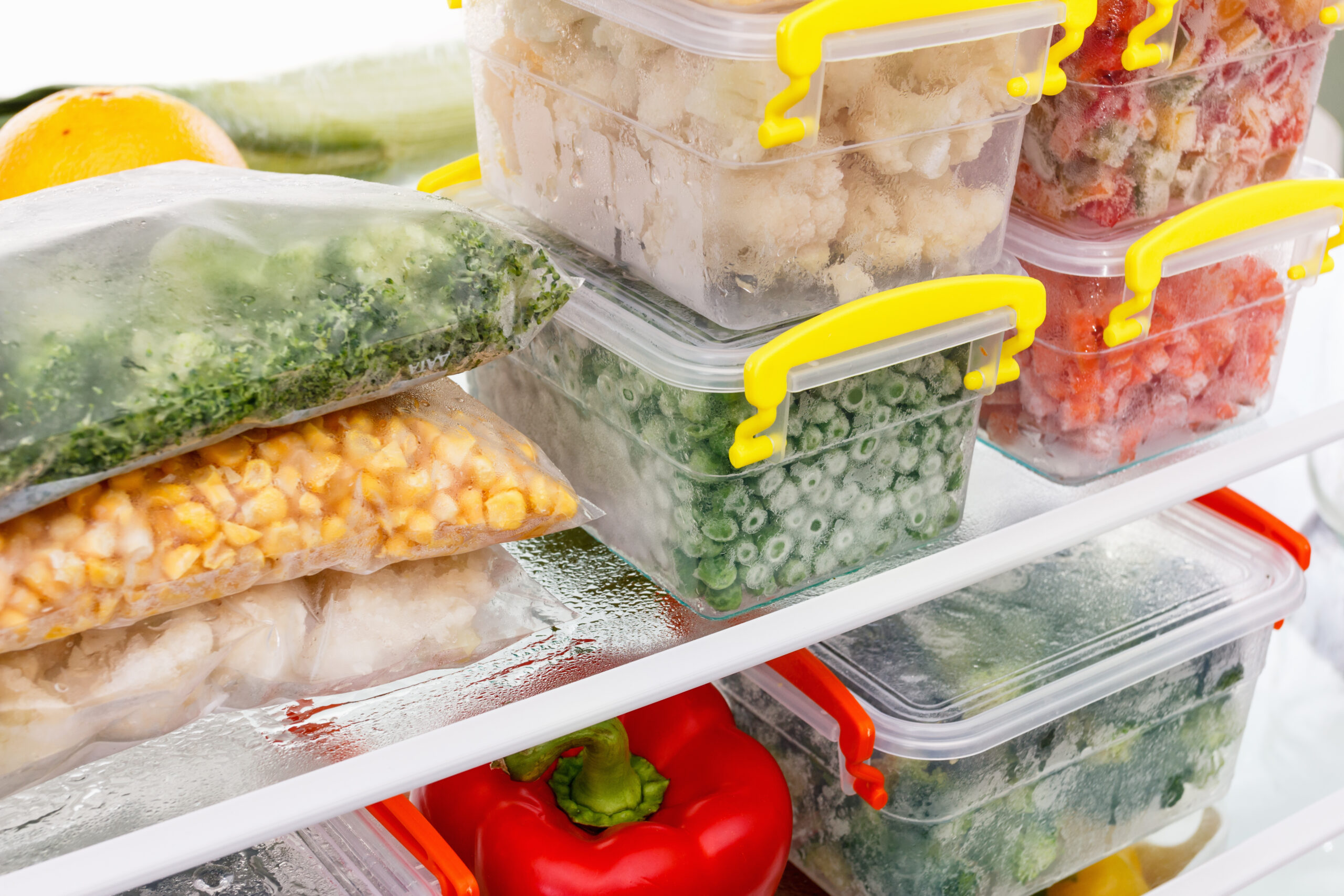 closeup of food in a fridge stacked in containers - feature image for RV fridge storage ideas