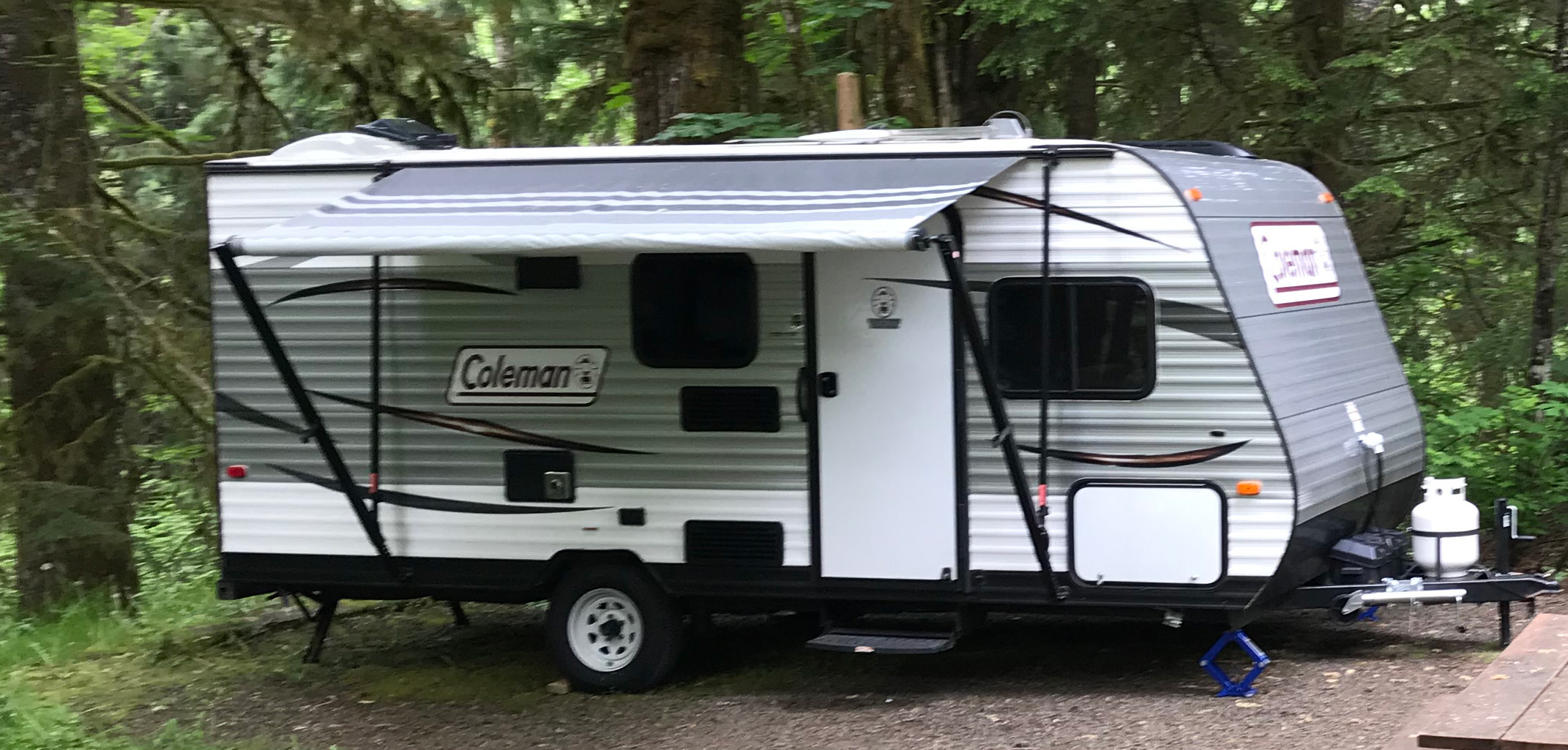 a Coleman trailer parked in the woods