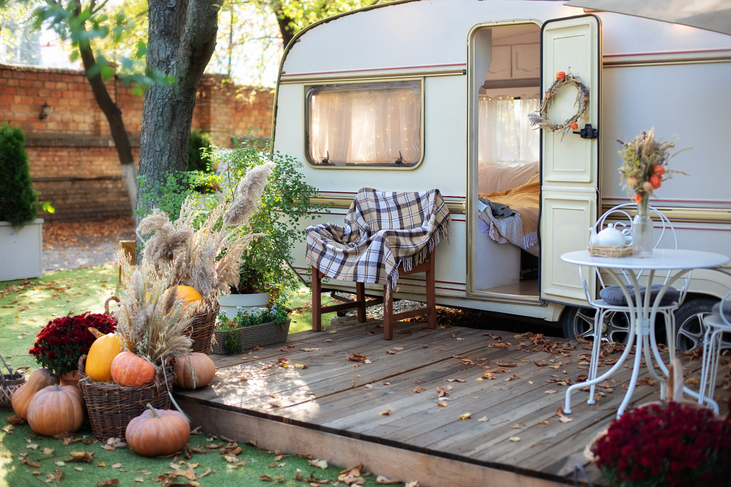 Vintage camper with wooden deck in front decorated with fall themed decorations - RV deck ideas