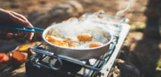 person cooking eggs on stove - feature image for camping breakfast ideas