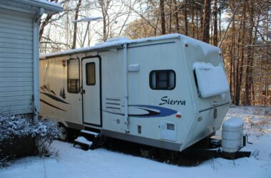 trailer in snow outside of house - feature image for how to winterize an RV