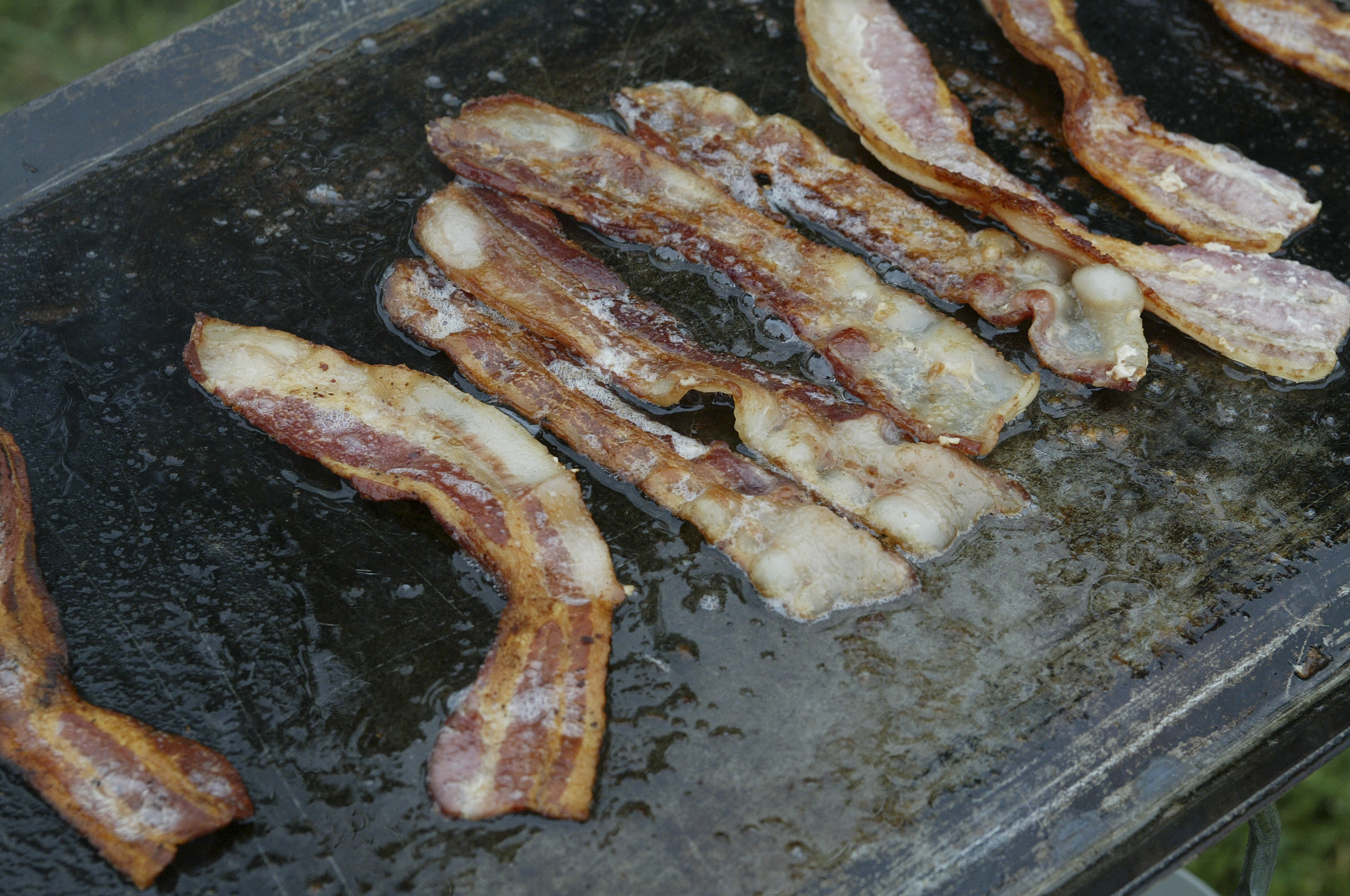 bacon sizzling in grease - feature image for What To Do With Leftover Bacon Grease 
