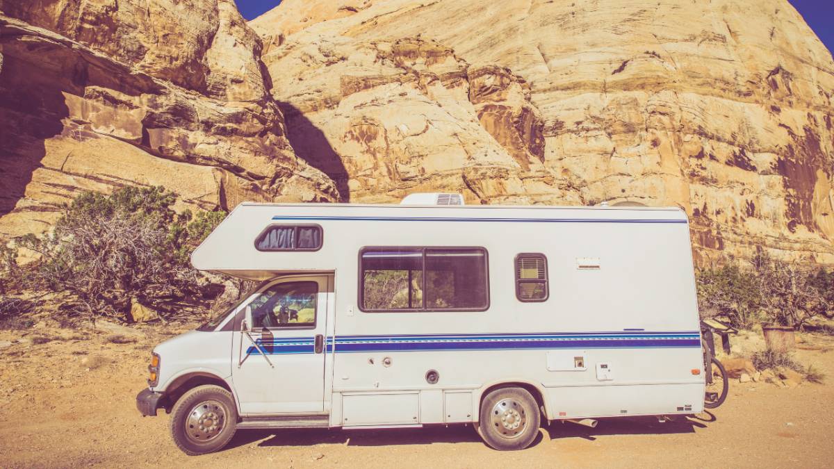 Vintage Class C Motorhome parked in front of a rugged mountain