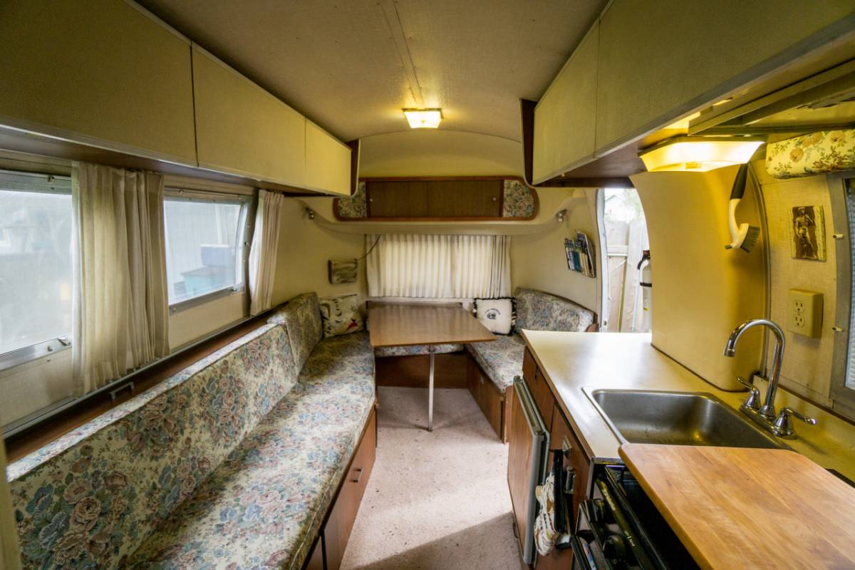 interior of vintage motorhome with long bench, kitchen counter, and dining table