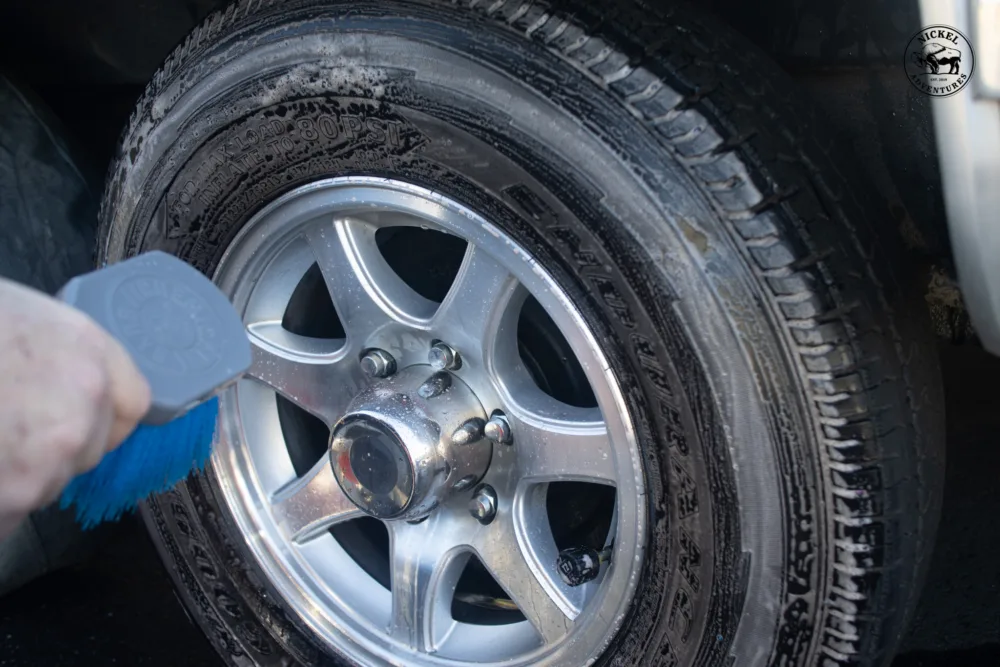 Tire being hand washed with a scrub brush.