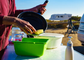 woman washes dishes outside when camping