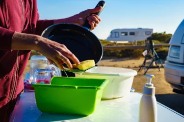 woman washes dishes outside when camping