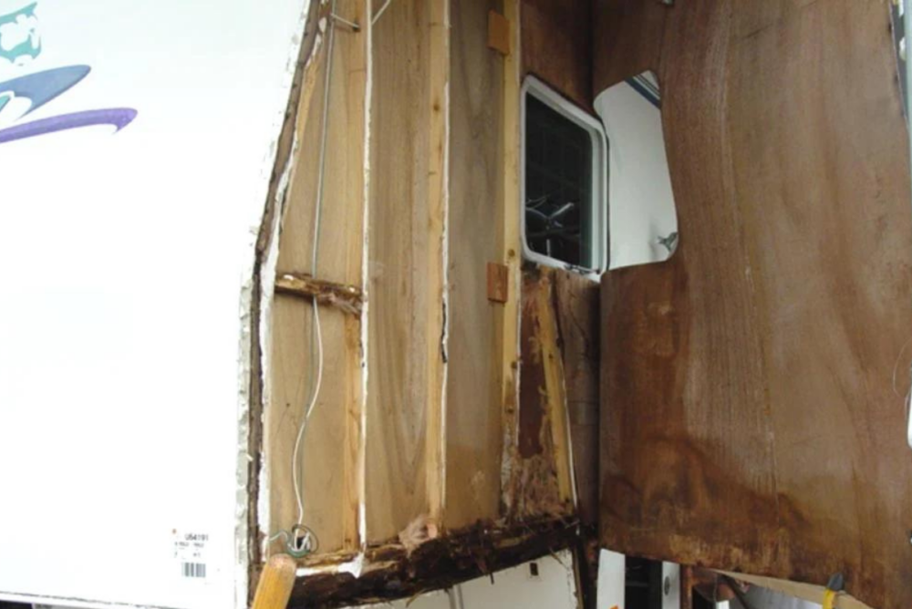 Fiberglass exterior layer peeled back from side of truck camper exposing wooden studs - delamination