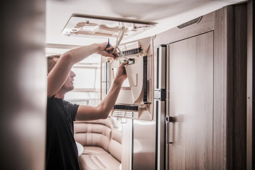 person working on RV air conditioner maintenance - preventative maintenance tips