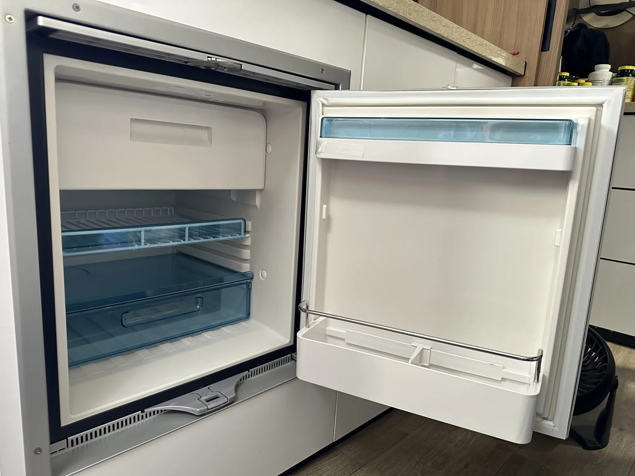 an open refrigerator in a kitchen next to a counter with a drawer on one side and a drawer on the other side