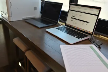 a laptop computer sitting on top of a wooden desk next to a laptop computer on top of a wooden desk