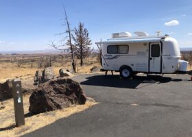 a camper parked on the side of a road in the middle of a dry grass and dirt field