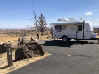a camper parked on the side of a road in the middle of a dry grass and dirt field