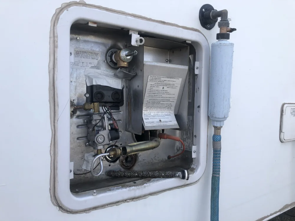 a water heater mounted to the side of a boat with a hose attached to the side of it