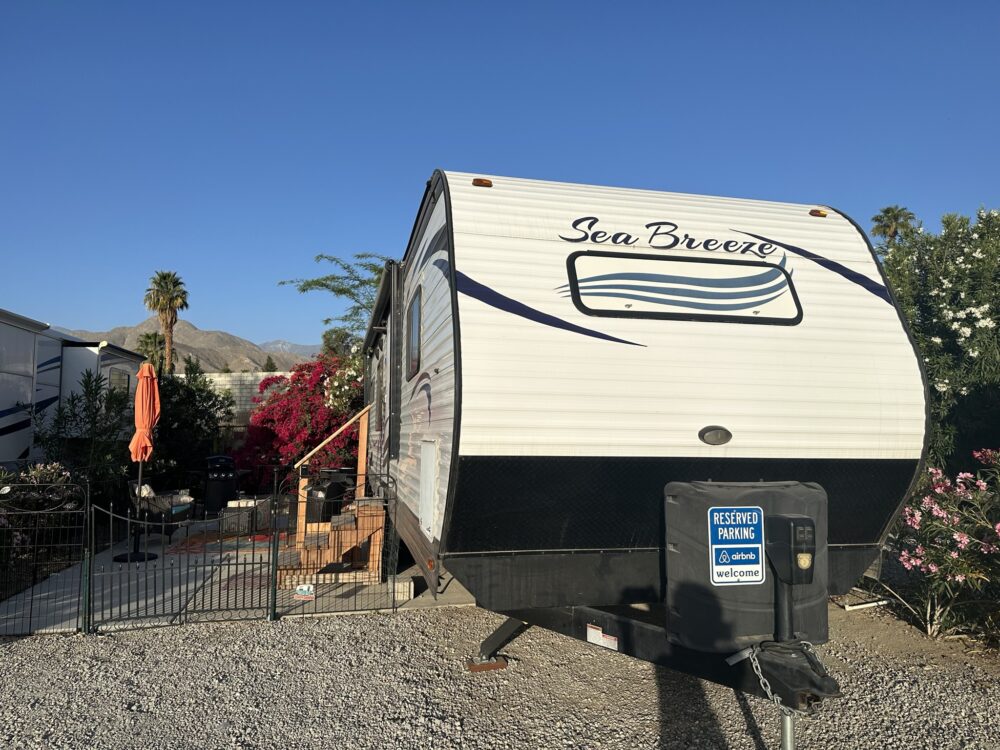 an rv parked in a gravel lot with a fence around it and a sign on the side of the trailer - image for beat the heat article