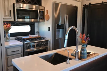a kitchen with a sink, stove, microwave, and a counter with a vase of flowers on it