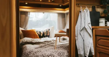 cozy bedroom interior in the trailer of mobile home remodeled with curtains, decorative pillows and overhead LED lights