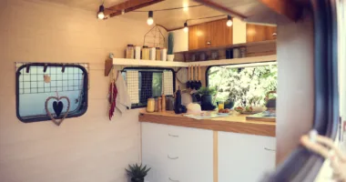 Stylish kitchen interior with different jars and utensils hanging from floating shelf in modern trailer.