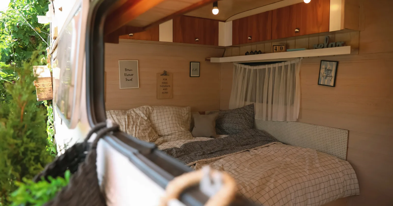Stylish interior with comfortable bed and pillows in modern trailer, view from outside
