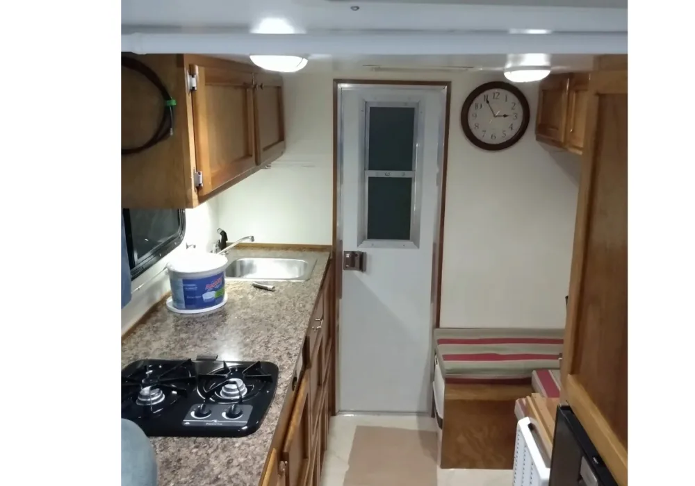 interior view of truck camper with dining area, kitchen counter, and door