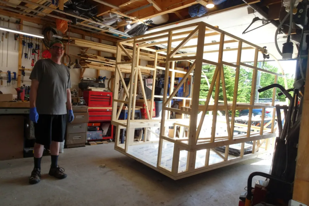 man standing next to the completed frame of a teardrop build in a garage