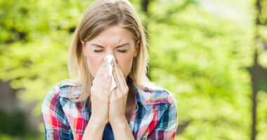 Woman with with outdoor allergy symptom blowing nose