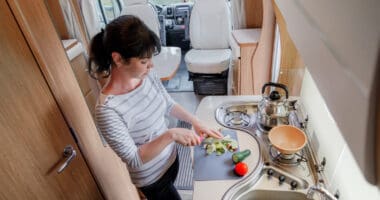 Woman cooking RV meals in camper kitchen